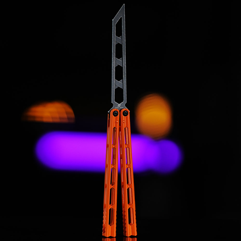 Armed Shark Prism Balisong Trainer in orange color back view showing skeletonized stainless steel training edge and handle design