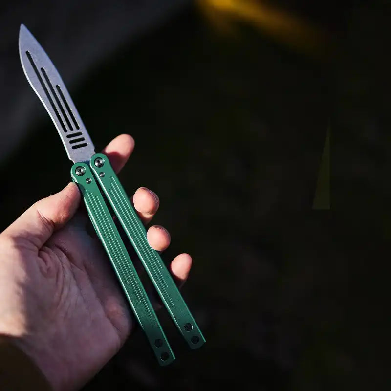 Armed Shark Balisong Trainer with green handle held in hand – practice tool view.