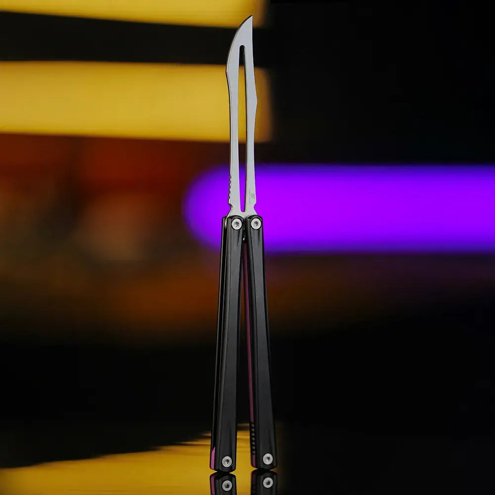 Front view of Armed Shark Eureka Balisong Trainer in matte black finish with polished stainless training edge, showcased under warm and purple studio lighting for a premium look