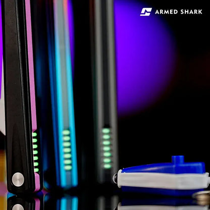 Back view of Armed Shark Eureka Balisong Trainer handles in pink, blue, and black gradient finishes with visible grip lines, shown alongside included pivot oil accessory under vibrant studio lighting